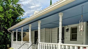A two-story house with a covered porch, white railings, and a hanging light fixture. - Turn-of-the-Century Gem! The Painted Lady.   (Bisbee)