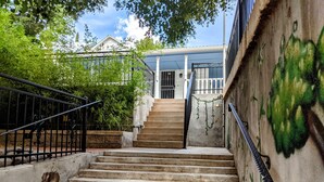A staircase leading to a building with a white facade and a green mural on the wall. - Turn-of-the-Century Gem! The Painted Lady.   (Bisbee)
