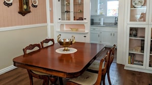 A dining room with a wooden table, chairs, a decorative bowl, and a wall-mounted clock. - Turn-of-the-Century Gem! The Painted Lady.   (Bisbee)