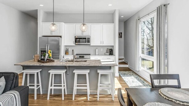 A modern kitchen with white cabinets, a central island with stools, stainless steel appliances, and pendant lighting. - Rooftop Deck w/ Grill/Golf!10min to Ole Opry & DT! (Nashville)