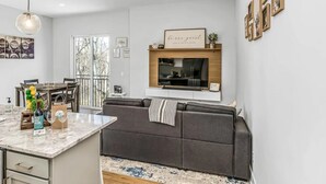 A modern kitchen with a marble countertop, a built-in oven, and a grey sofa. - Rooftop Deck w/ Grill/Golf!10min to Ole Opry & DT! (Nashville)