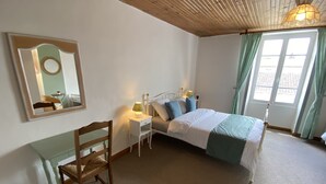 Een slaapkamer met een bed, nachtkastjes, een stoel, een spiegel en een raam met gordijnen.