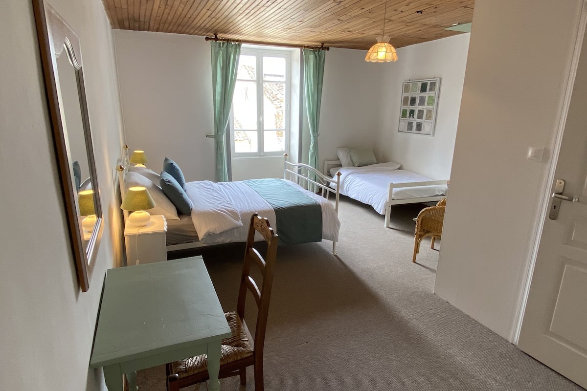 Een slaapkamer met twee bedden, een tafel en een stoel.