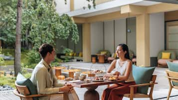Un espace extérieur aménagé avec une table pour deux, entouré de verdure et de mobilier moderne.