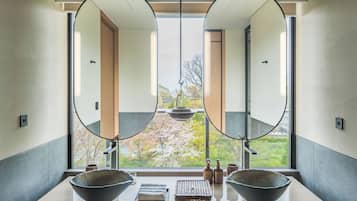A bathroom with a large window, two round mirrors, and a central sink with two bowls.