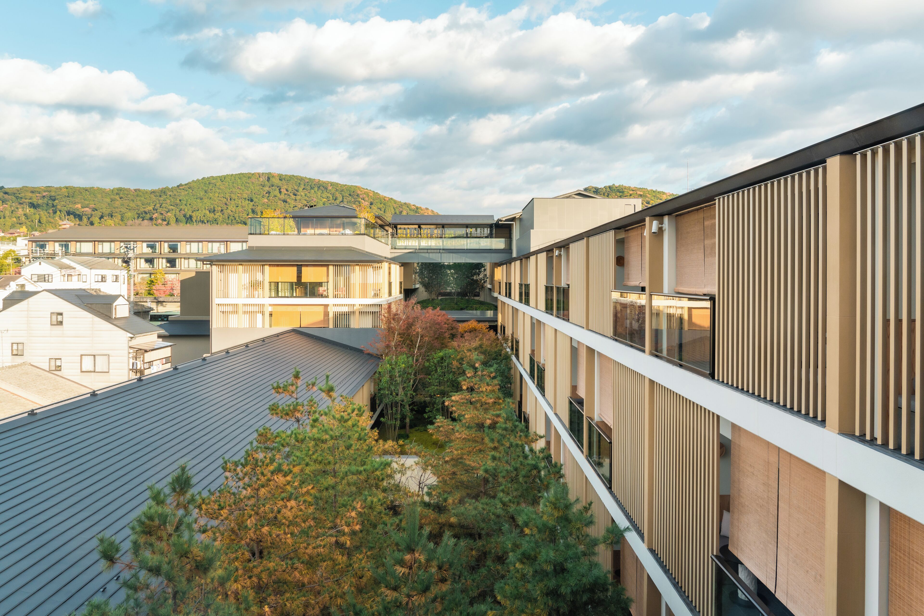 A modern building with a flat roof, a covered walkway, and a view of a hilly landscape.