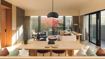A modern dining area with a wooden table, cushioned seating, and a hanging light fixture.
