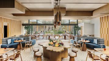Un espace intérieur vaste et lumineux, avec une grande table en bois au centre, entourée de sièges, de grandes fenêtres et un plafond au design moderne.