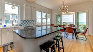 A modern kitchen with a large island, white cabinets, and a view of the ocean. - Seascapes 714 Ocean Blvd. Charming, Ocean Front, Private Pool (Isle Of Palms)