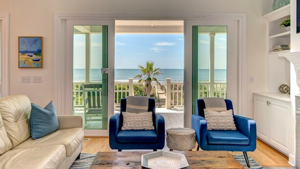A living room with a view of the sea, two blue armchairs, a beige sofa, and a wooden coffee table. - Seascapes 714 Ocean Blvd. Charming, Ocean Front, Private Pool (Isle Of Palms)