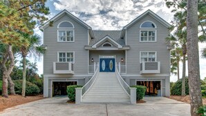 A two-story house with a central entrance, a covered porch, and a staircase leading to the front door. - Seascapes 714 Ocean Blvd. Charming, Ocean Front, Private Pool (Isle Of Palms)