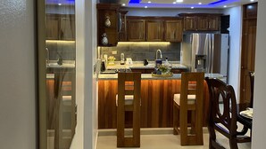 Une cuisine moderne avec des meubles en bois, un îlot central et un coin repas avec des chaises.