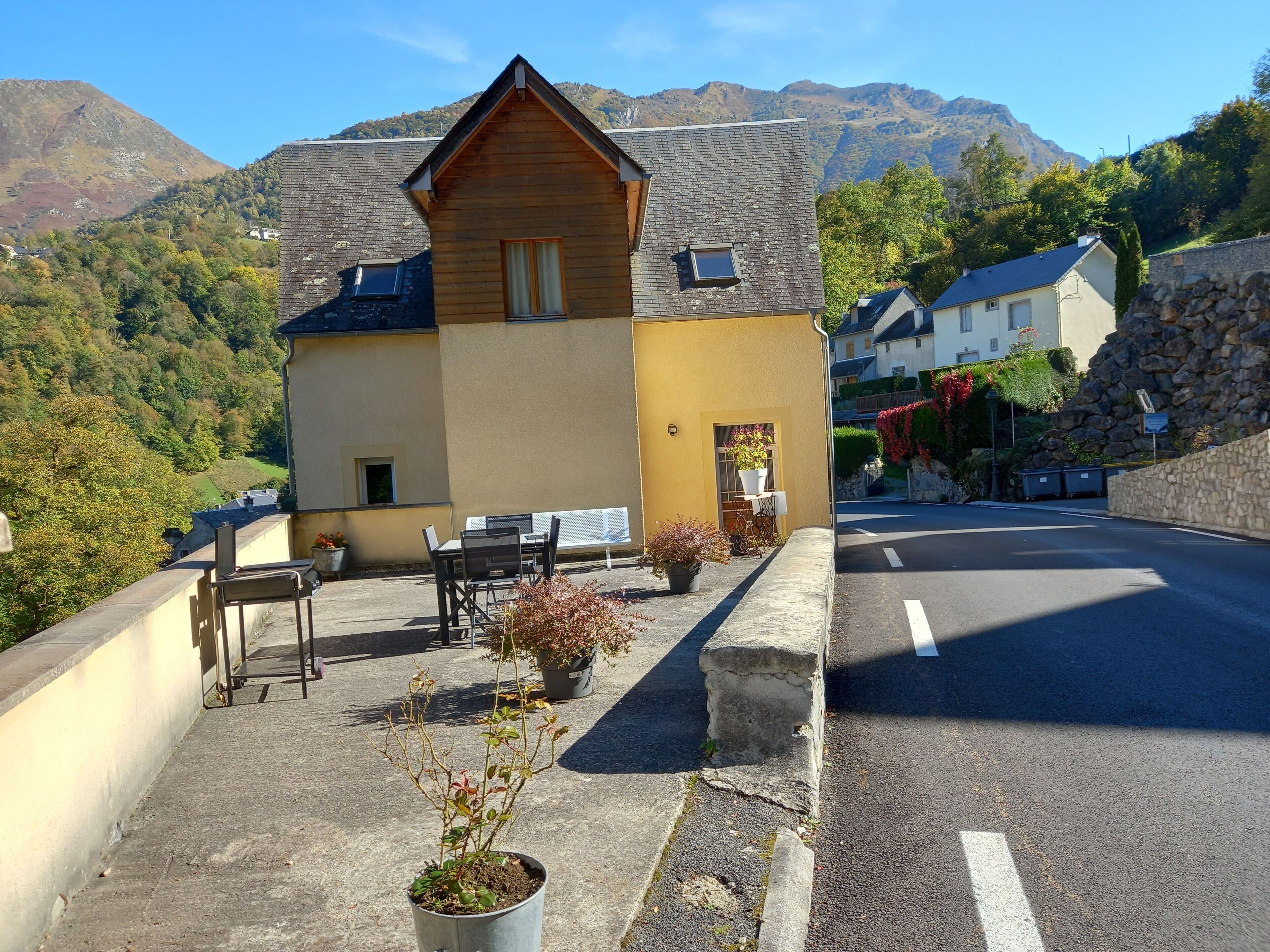 A mountain-view hotel with a wooden facade, outdoor seating, and a stone wall.