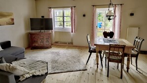 Ett mysigt vardagsrum med en soffa, TV, ett träskåp och ett matbord med stolar.