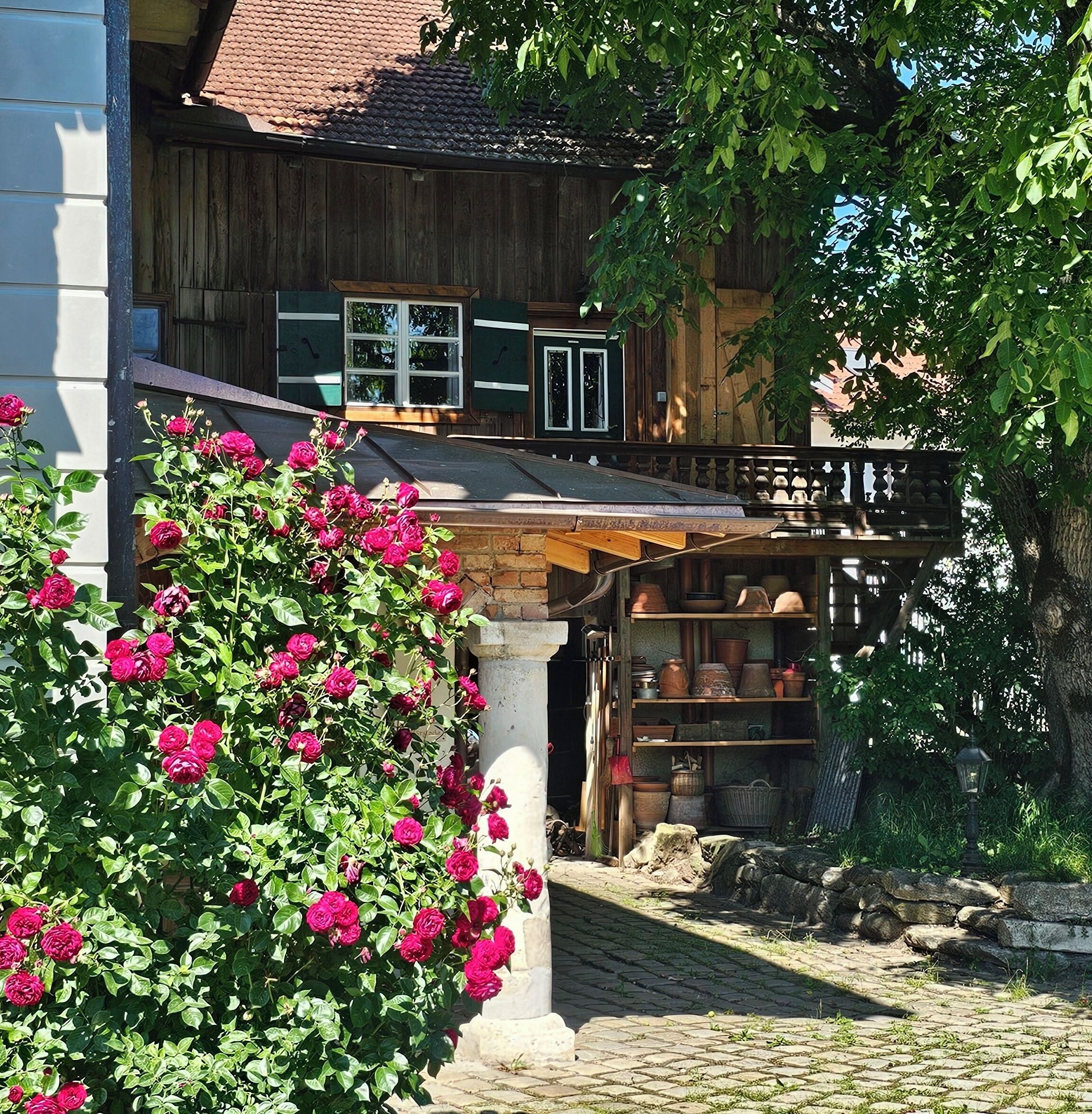A traditional wooden house with a balcony, a garden with blooming flowers, and a stone pathway.