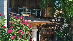 Ett traditionellt trähus med en balkong, en trädgård full av blommande växter och en gång av sten.