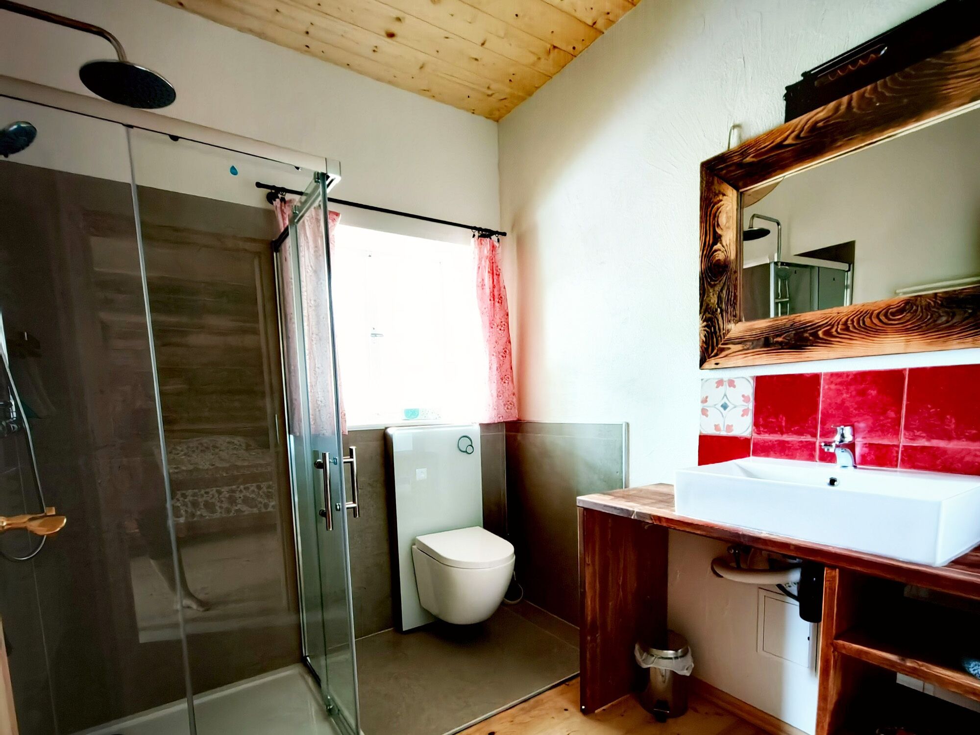Un bagno con box doccia in vetro, un water e un lavabo su mobile in legno.