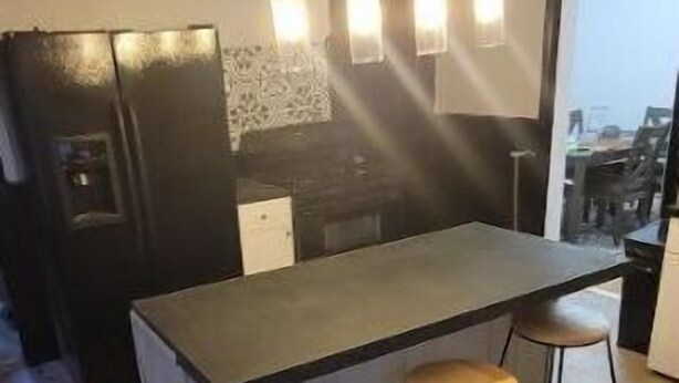 A modern kitchen with a central island, bar stools, and pendant lighting.