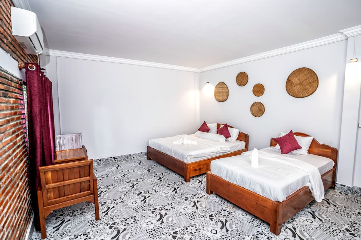 A hotel room with two beds, a small wooden table, and a decorative wall with circular patterns.