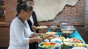 Una mesa de buffet con diversos alimentos y una persona sirviendo.