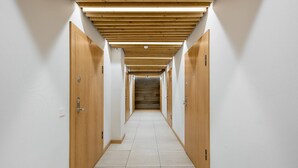 Un pasillo con puertas de madera y suelo de baldosas, que conduce a una escalera.