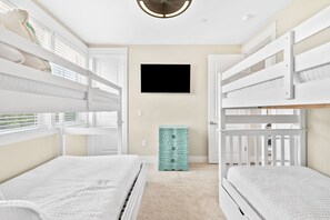 A child’s bedroom with bunk beds, a flat-screen TV, and a teal dresser.