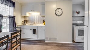 A compact kitchen with white cabinets, a sink, a stove, and a clock on the wall. - Pet-Friendly Auburn Apartment w/ Balcony! (Auburn)