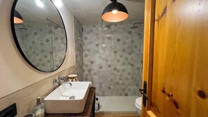 Ein Badezimmer mit einem Holzkosmetikschrank, einem großen Spiegel, einer Dusche und einer Toilette.
