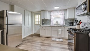 A kitchen with white cabinets, a stainless steel refrigerator, a gas stove, and a microwave. - Central Auburn Apartment w/ Porch: Pets Welcome! (Auburn)
