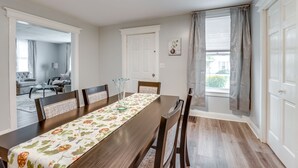 A dining room with a long table, chairs, a vase, and a view of a living room through an open door. - Central Auburn Apartment w/ Porch: Pets Welcome! (Auburn)