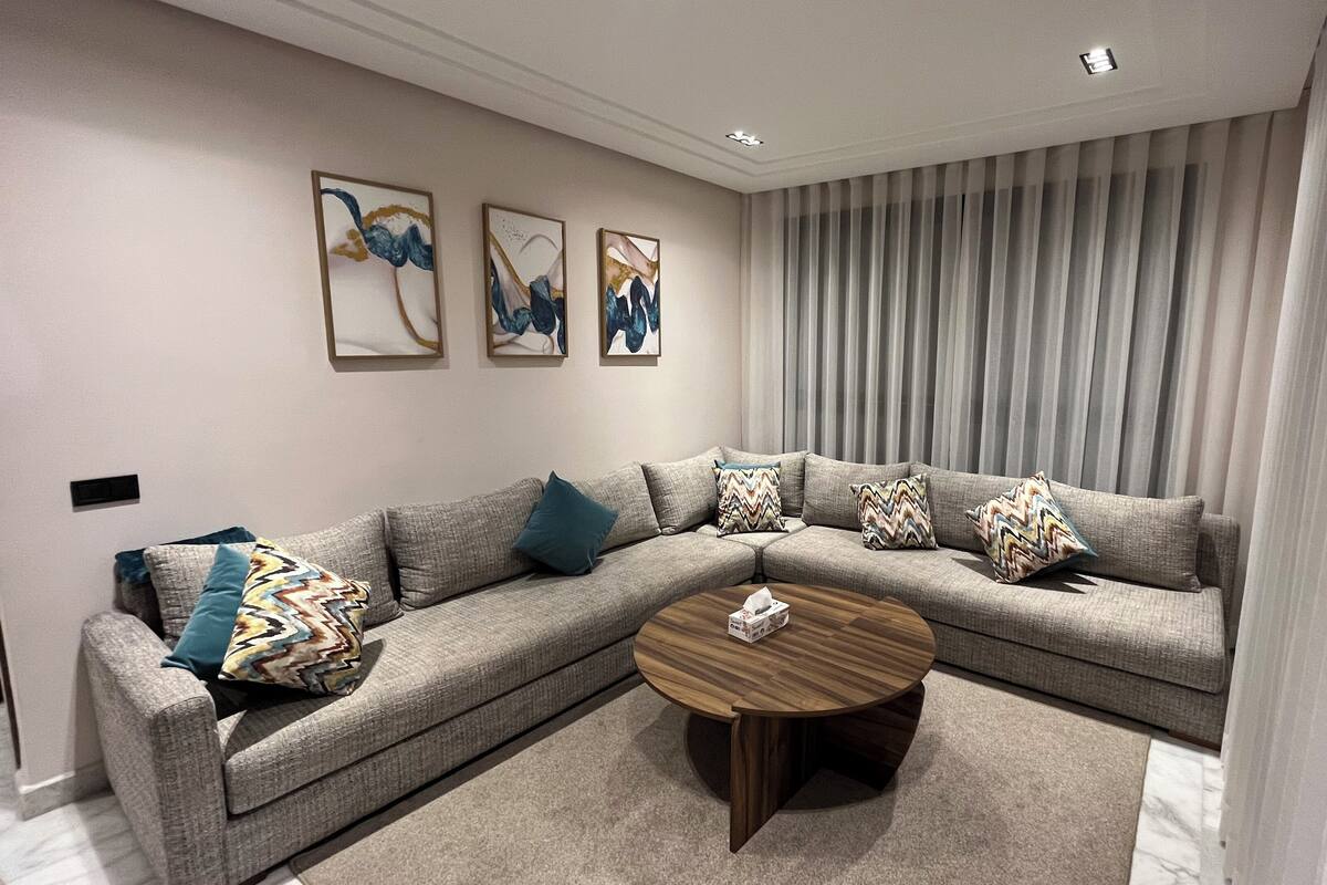 A modern living room with a grey sectional sofa, a wooden coffee table, and abstract wall art.