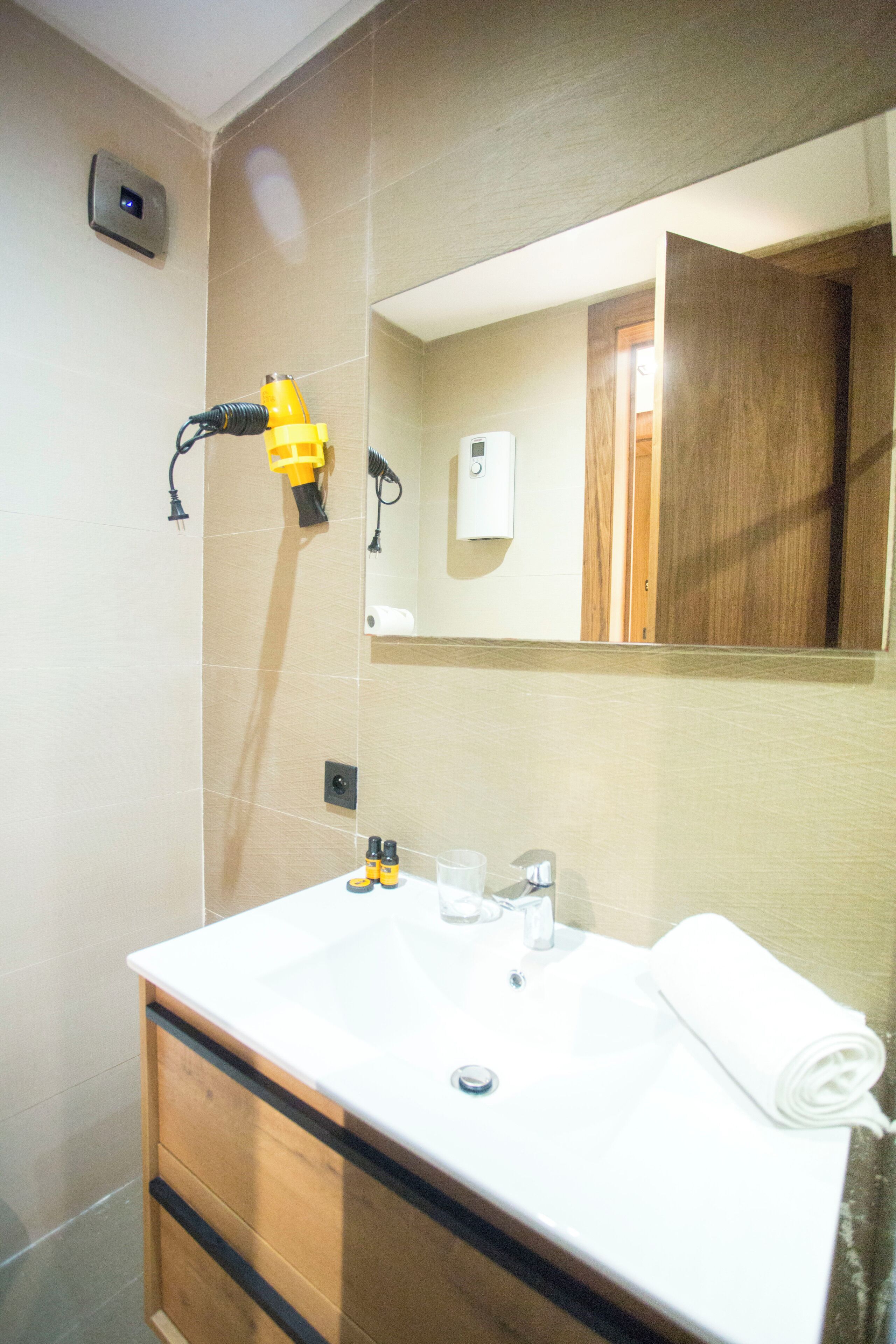 A bathroom with a white sink, a mirror, a towel, and a towel dispenser.