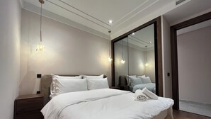 A modern bedroom with a large bed, bedside tables, a mirror, and recessed ceiling lighting. - Les Joyeux Luxury Suites & Appart (Casablanca)