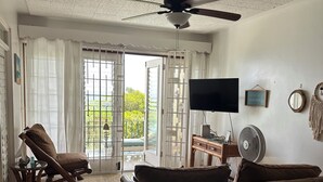 A spacious living room with a ceiling fan, a sofa, a chair, and a television.