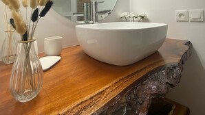 Ein modernes Badezimmer mit einem großen, ovalen Waschbecken, einem runden Spiegel und einer Holzauslage.