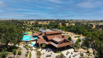 Relax in a scenic setting with expansive views of hills and open fields, surrounded by lush greenery and multiple pools.