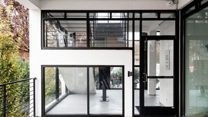 A modern building with a glass entrance, a visible staircase, and a balcony with greenery. - La Penelope – Walk to Ponce City Market + Rooftop (Atlanta)