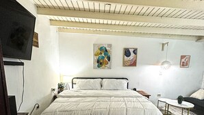 Ein Schlafzimmer mit einem Bett, einem Fernseher, einem kleinen Tisch und Bildern an der Wand.