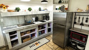 Eine moderne Küche mit einem Edelstahlkühlschrank, einer Mikrowelle und einem eingebauten Backofen. Es gibt eine Arbeitsplatte mit Spüle und einer Spritzschutzverkleidung mit Dekoration.