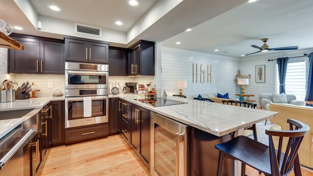 A modern kitchen with dark cabinets, stainless steel appliances, and a marble island. - Amazing sunrises & beach views from private balcony & steps from the sand!! (Jacksonville Beach)