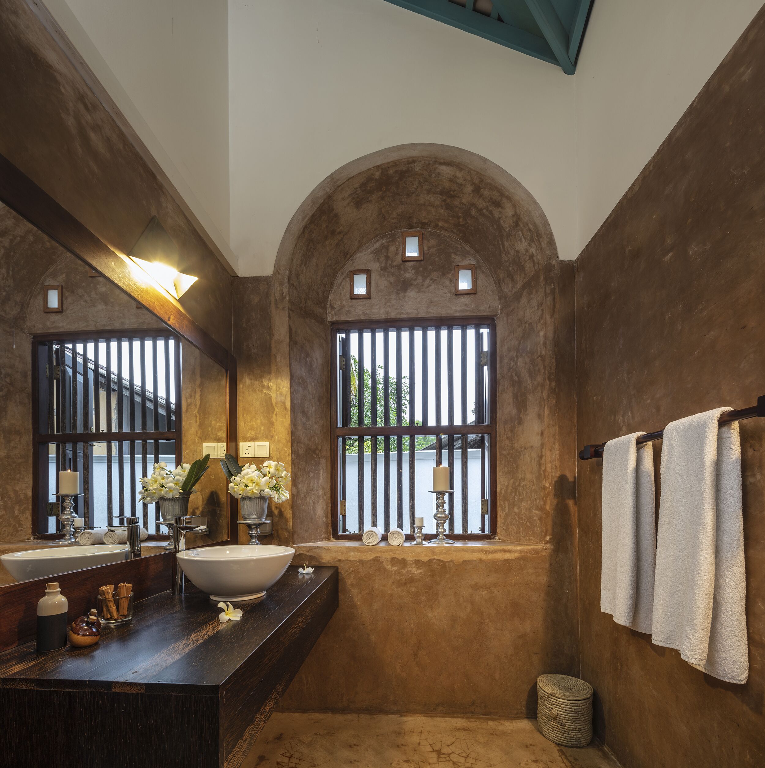 Une salle de bain dotée d’une grande fenêtre en arc de cercle, d’un lavabo avec un miroir et d’un porte-serviettes.