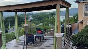 Un espace extérieur abrité, doté de chaises et d’une table, offrant une vue sur un paysage verdoyant.