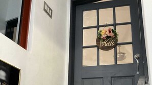 Une porte bleu foncé avec un panneau en verre dépoli et une pancarte sur laquelle est écrit « Bonjour ».