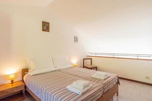 A bedroom with a bed, nightstands, a chair, and a window with a view. - CO.RI. Appartamenti 5, Menaggio, Italy (Menaggio)