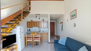 En moderne lejlighed med trappe, spiseplads, køkken og stue med sofa.