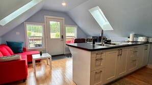 Ein modernes Loft mit Küche, Essbereich und einem roten Sofa.