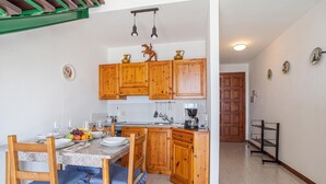 A kitchen with wooden cabinets, a dining table with chairs, and a coffee machine.