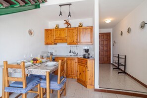 A kitchen with wooden cabinets, a dining table with chairs, and a coffee maker. - CO.RI. Appartamenti 2, Menaggio, Italy (Menaggio)