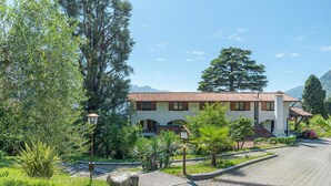 A building with a tiled roof, surrounded by greenery and a paved driveway. - CO.RI. Appartamenti 2, Menaggio, Italy (Menaggio)