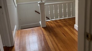Ein Zimmer mit Holzboden, einer weißen Geländer und einem Fenster mit Blick ins Freie.